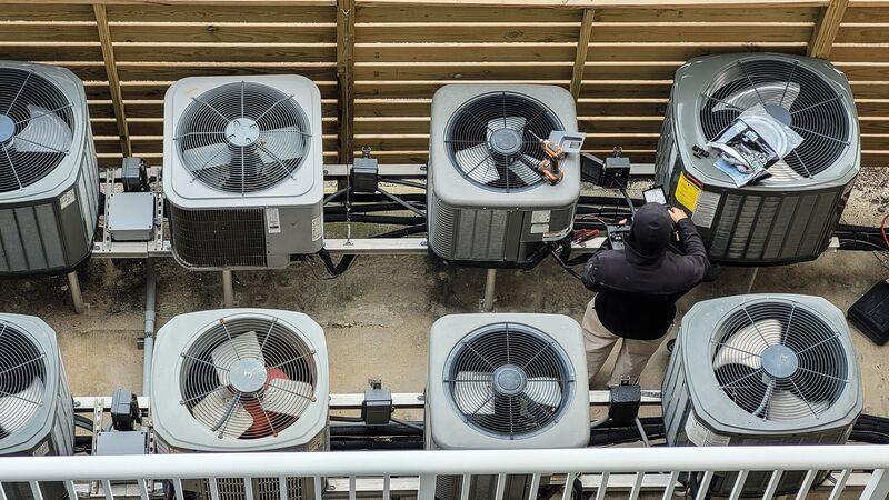 Technician servicing a rooftop array of air-conditioning condenser units